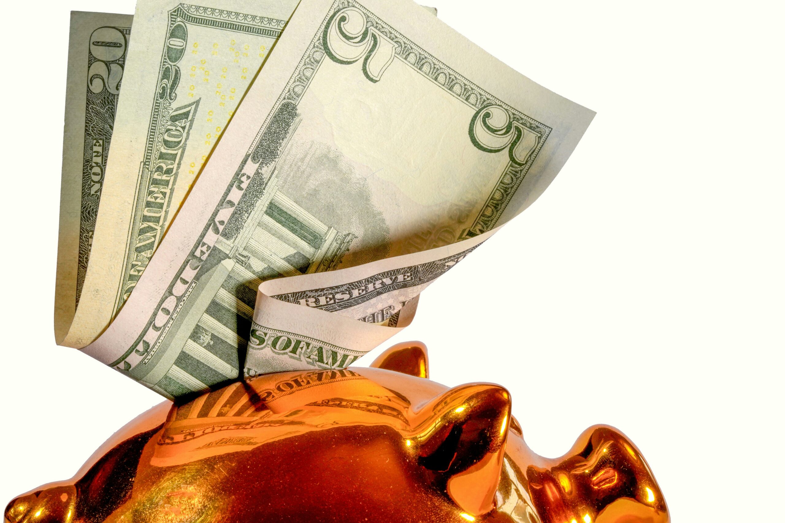 Dollarbiljetten steken uit de gleuf van een glanzend oranje spaarvarken