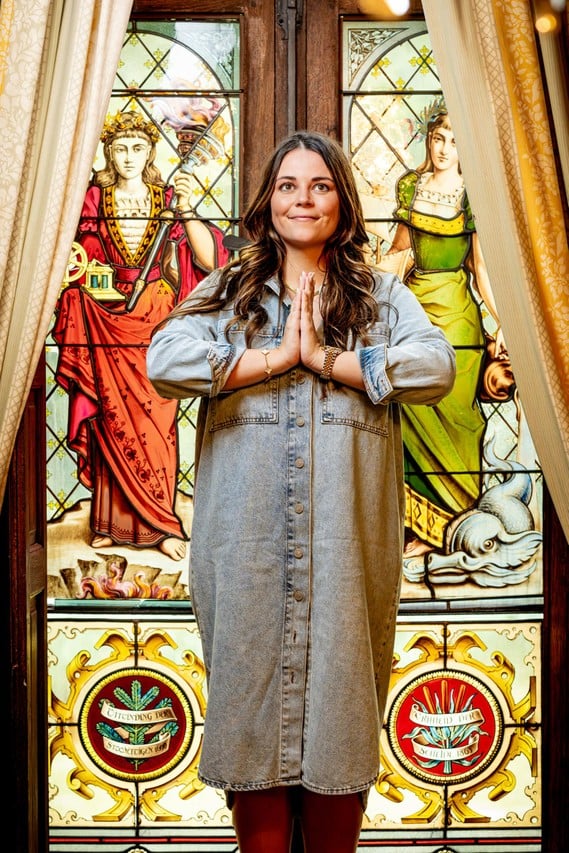 Charlotte Van Brabander staand voor een glas-in-loodraam