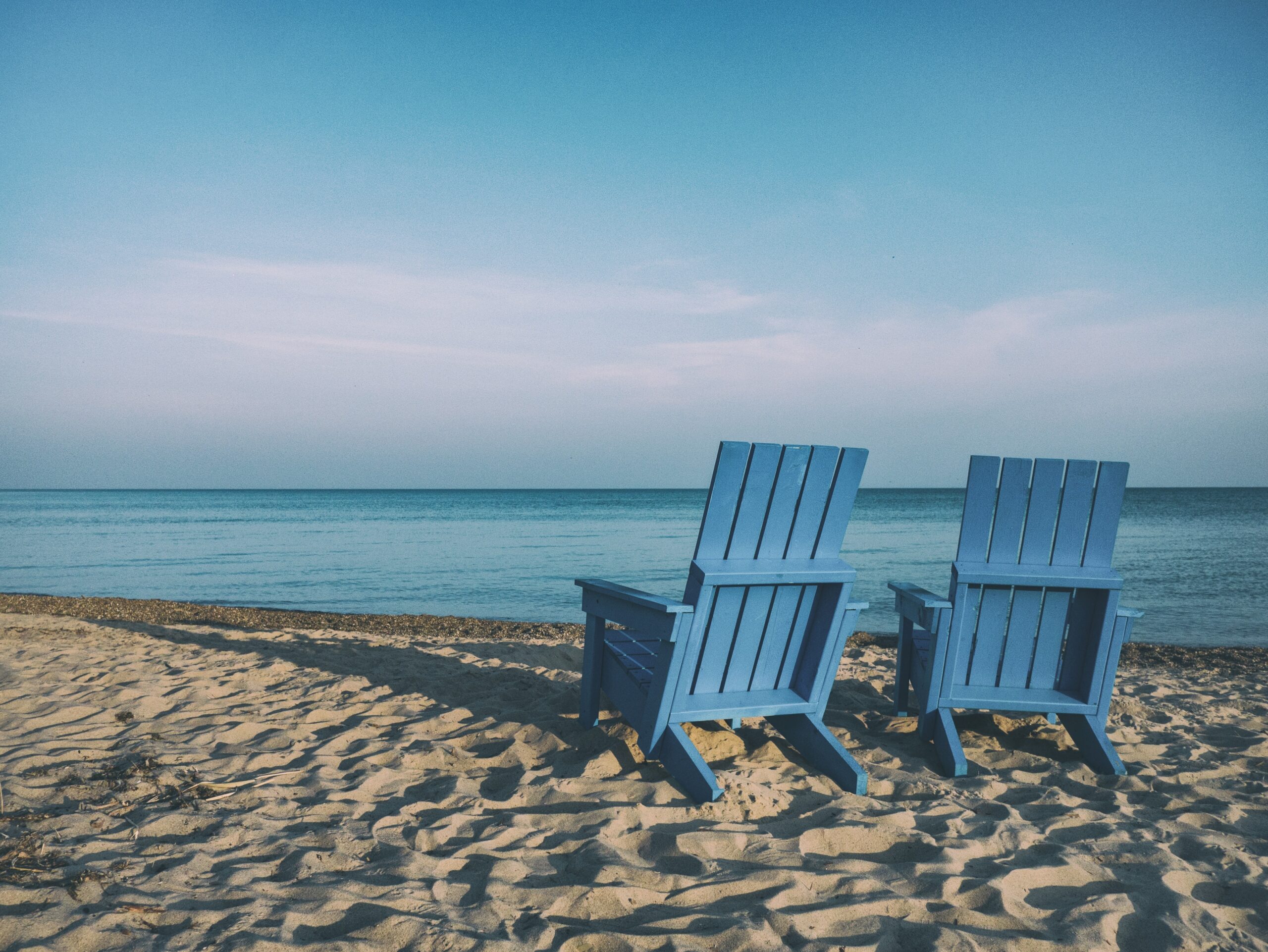 Twee blauwe strandstoelen op het strand aan zee